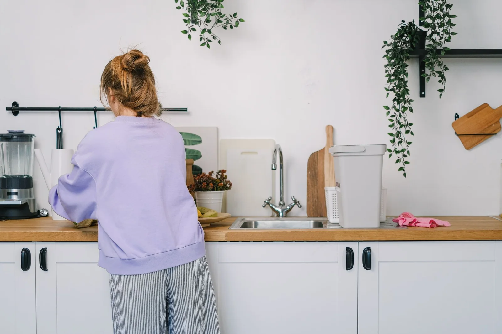 Back view of a woman doing housework at a kitchen worktop