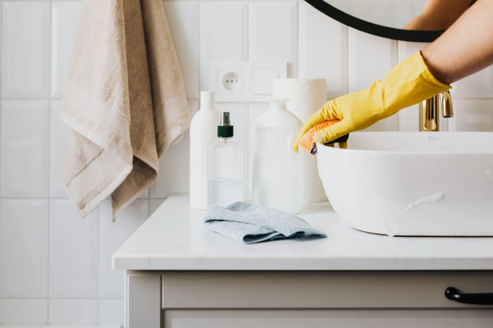 Yellow-gloved hand wiping a white bathroom basin