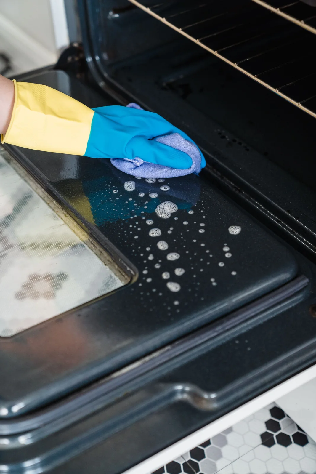 Gloved hand cleaning the interior of an open oven